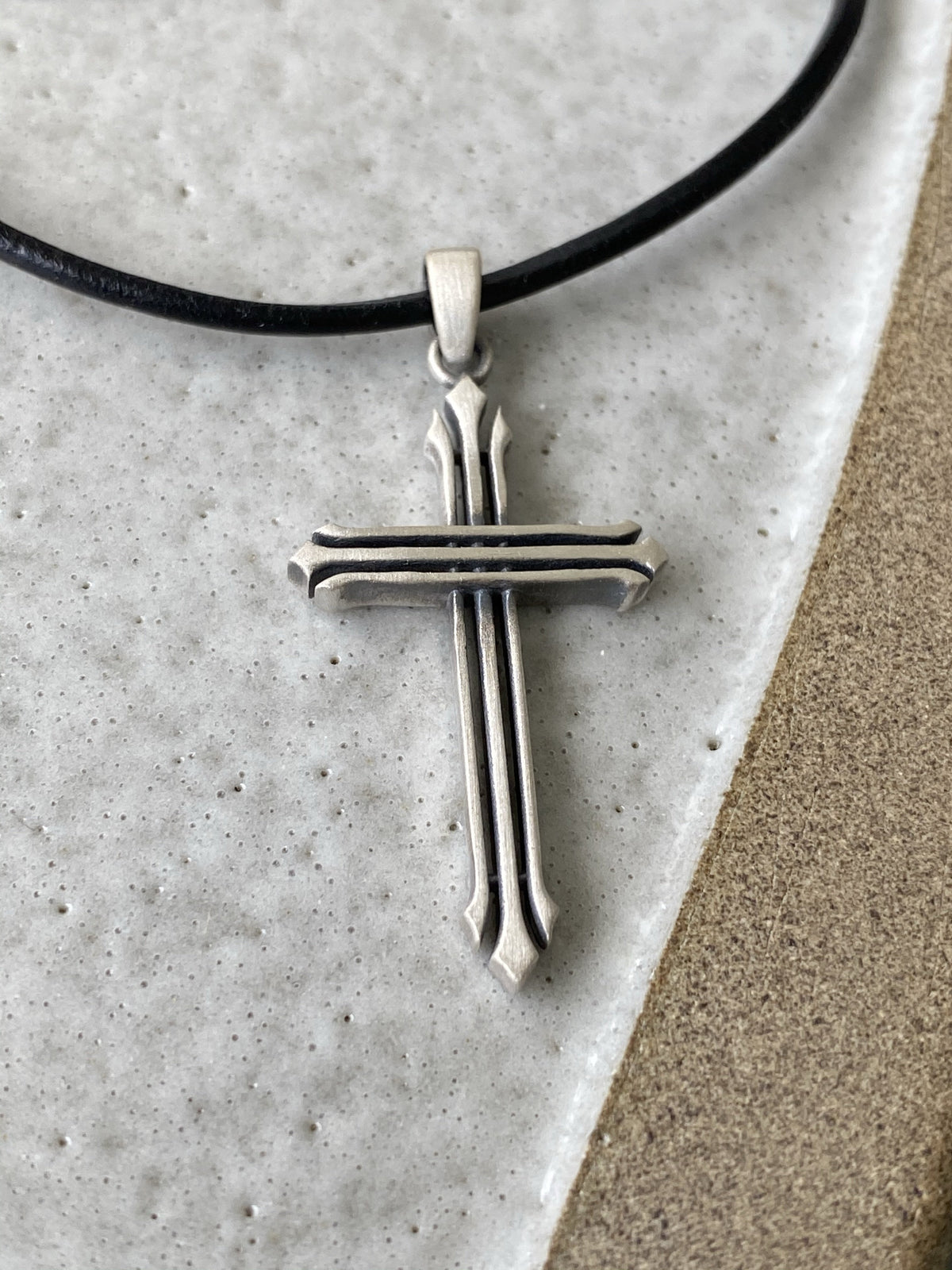 Silver cross necklace with a black leather cord 